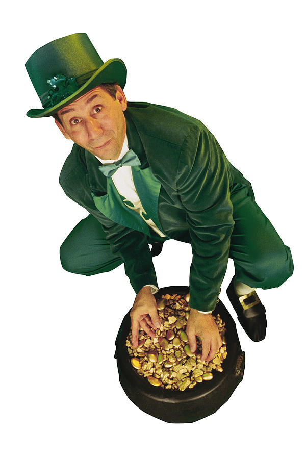Leprechaun dipping hands into pot of gold Photograph by Comstock