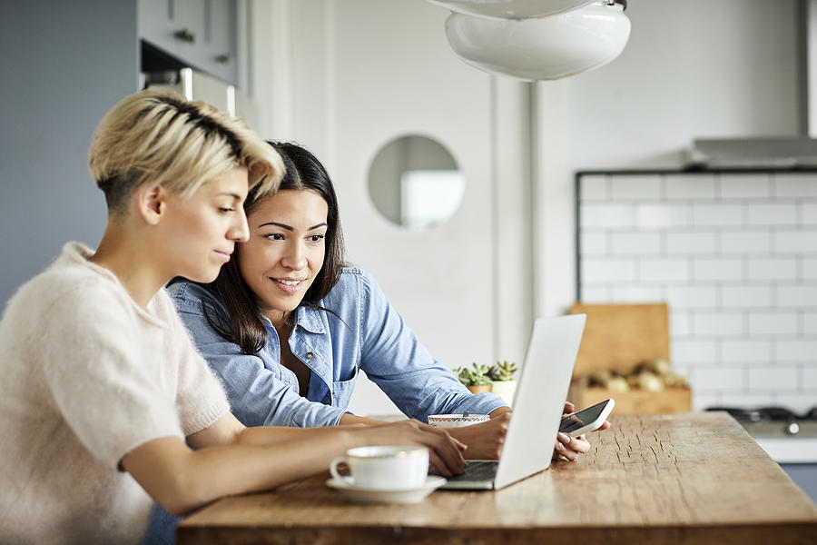 Lesbian couple with laptop on table at home Photograph by Morsa Images