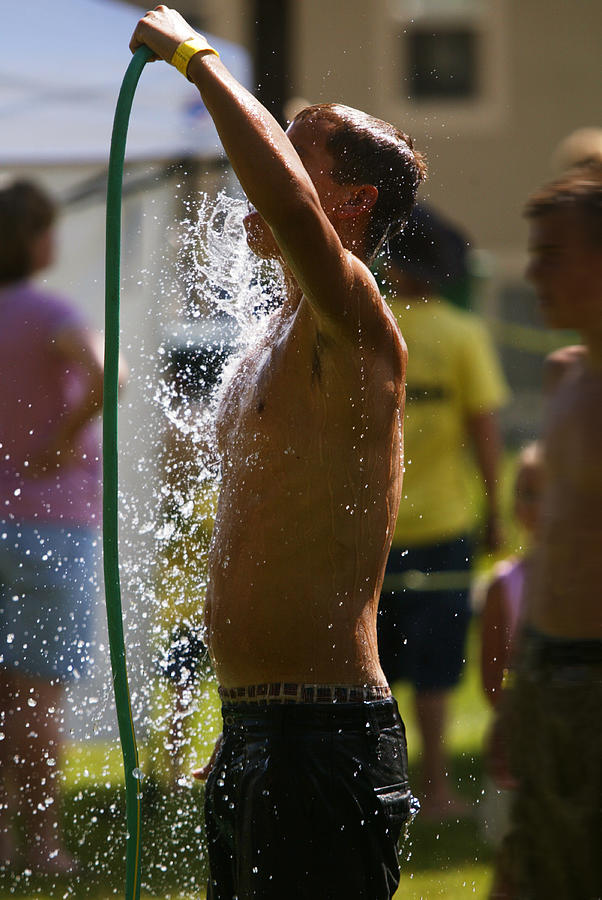 Lifestyle Photo Of A Caucasian Male Child In A Swimsuit As He Sprays Himself With A Hose Photograph by Photodisc
