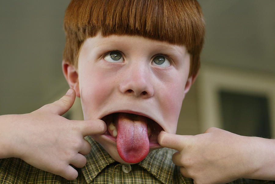 Lifestyle Photo Of A Little Redheaded Boy As He Sticks His Tongue Out And Makes A Funny Face Photograph by Photodisc