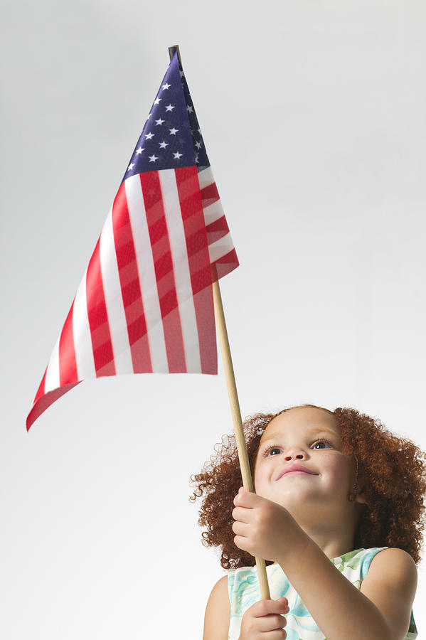 Lifestyle Portrait Of A Female Child As She Looks Up At An American Flag Photograph by Photodisc