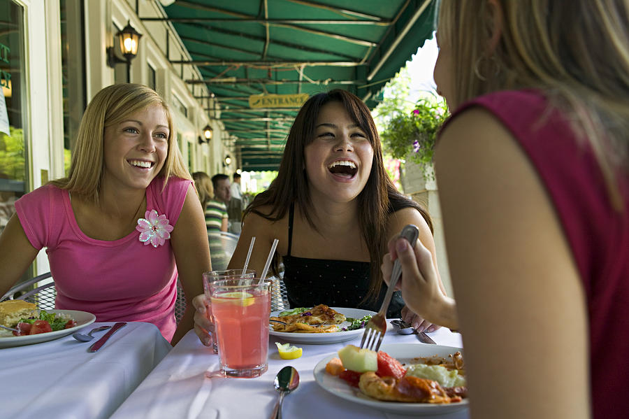 Lifestyle Portrait Of A Group Of Three Teenage Female Friends As They Eat At A Sidewalk Cafe Photograph by Photodisc