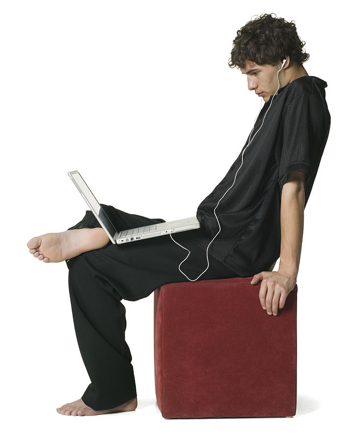 Lifestyle Portrait Of Young Adult Male He Sits And Listens To Headphones From His Laptop Computer Photograph by Photodisc