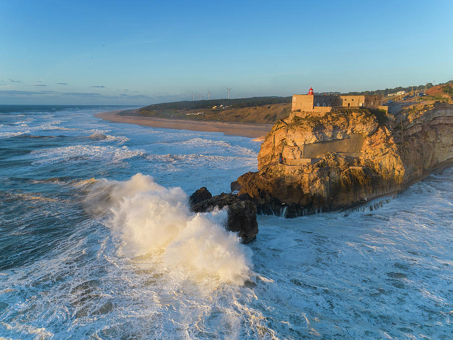 Lighthouse and big waves at in Nazare Photograph by Mikhail Kokhanchikov