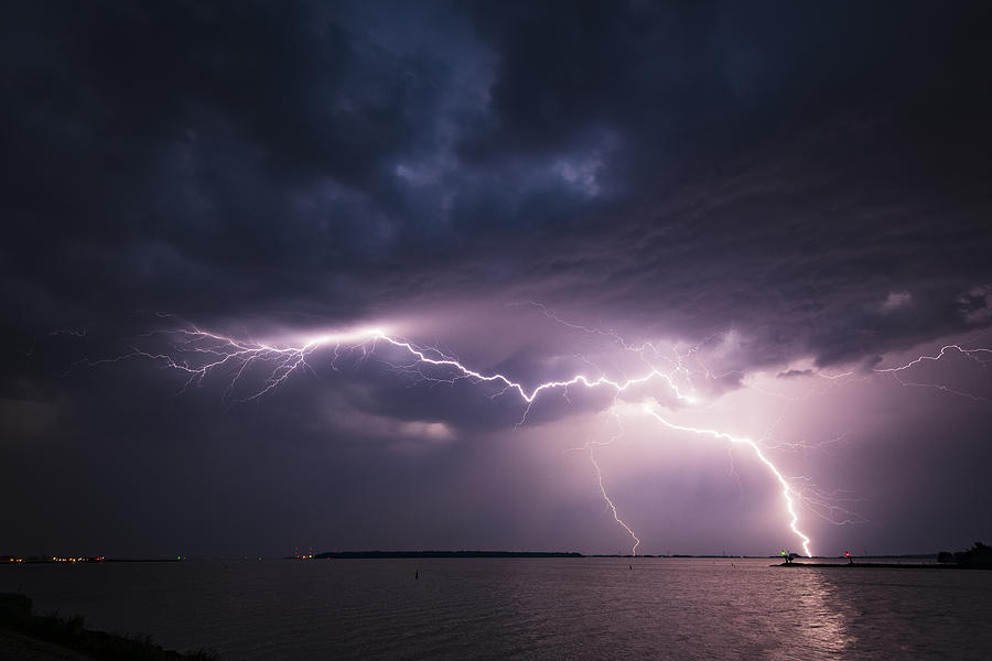 Lightning in the dark night sky over a lake during summer Photograph by Sjo