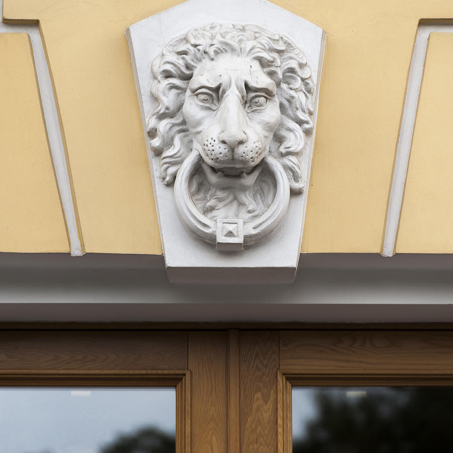 Lions face statue carved on the wall of a building Photograph by Fotosearch