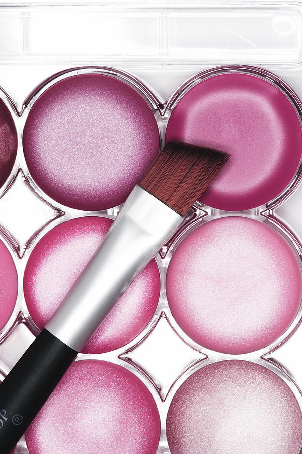 Lip brush resting on pink lip gloss palette, close-up, elevated view Photograph by Martin Poole