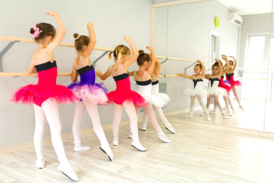 Little ballerinas in tutu using barre and practicing postures. Photograph by EmirMemedovski