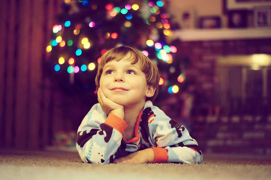 Little boy daydreaming next to Christmas tree Photograph by Annette Bunch