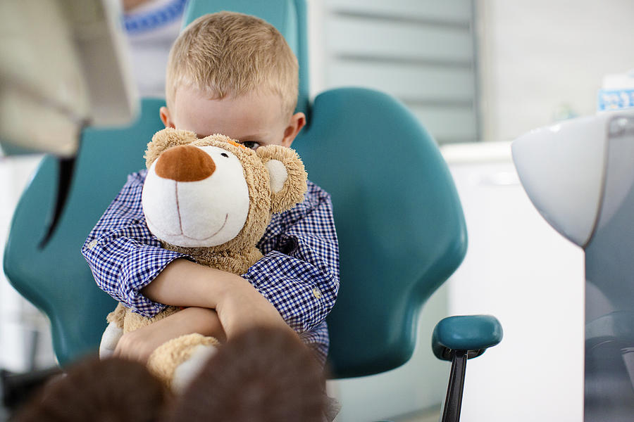 Little boy holding a teddy bear in his arms at dentists office Photograph by Milanvirijevic