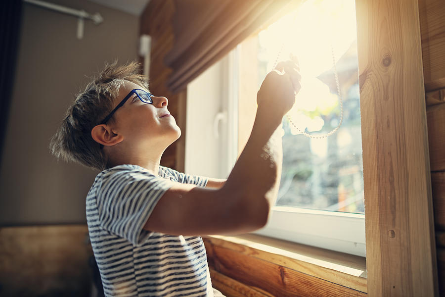 Little boy opening the roller blinds in the morning Photograph by Imgorthand