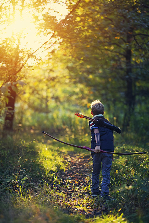 Little boy playing with bow in forest Photograph by Imgorthand