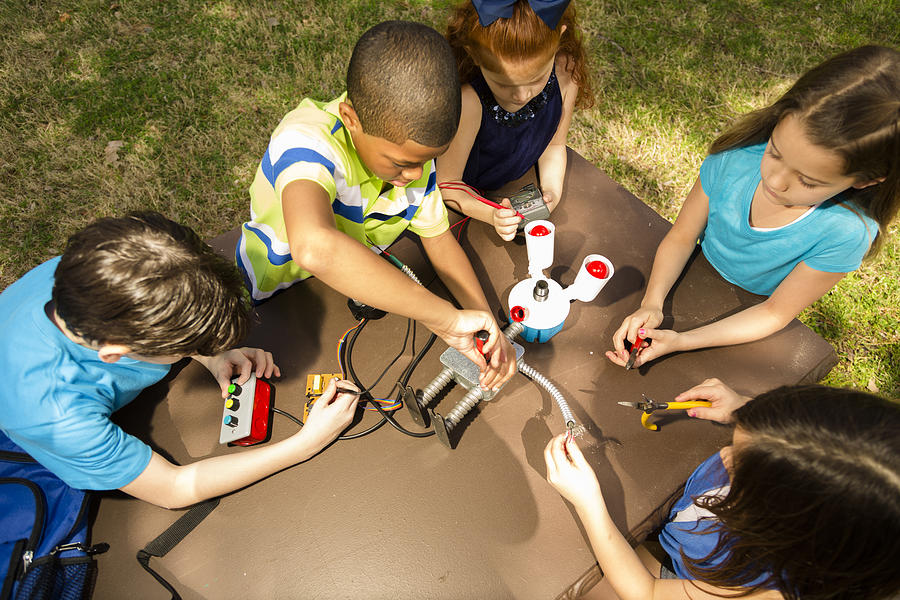 Little engineers!  Ethnic elementary children collaborate on robot they created. Photograph by Fstop123