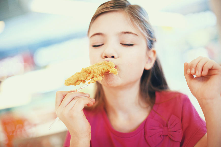 Little girl eating fried chicken. Photograph by Gilaxia