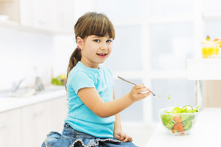 Little girl eating salad. Photograph by Skynesher