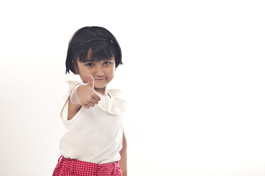 Little girl giving thumbs up Photograph by IndiaPix/IndiaPicture