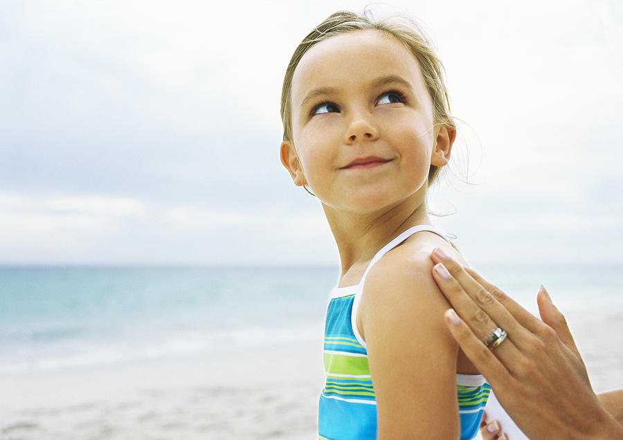 Little girl having sunscreen rubbed into shoulder Photograph by Sigrid Olsson