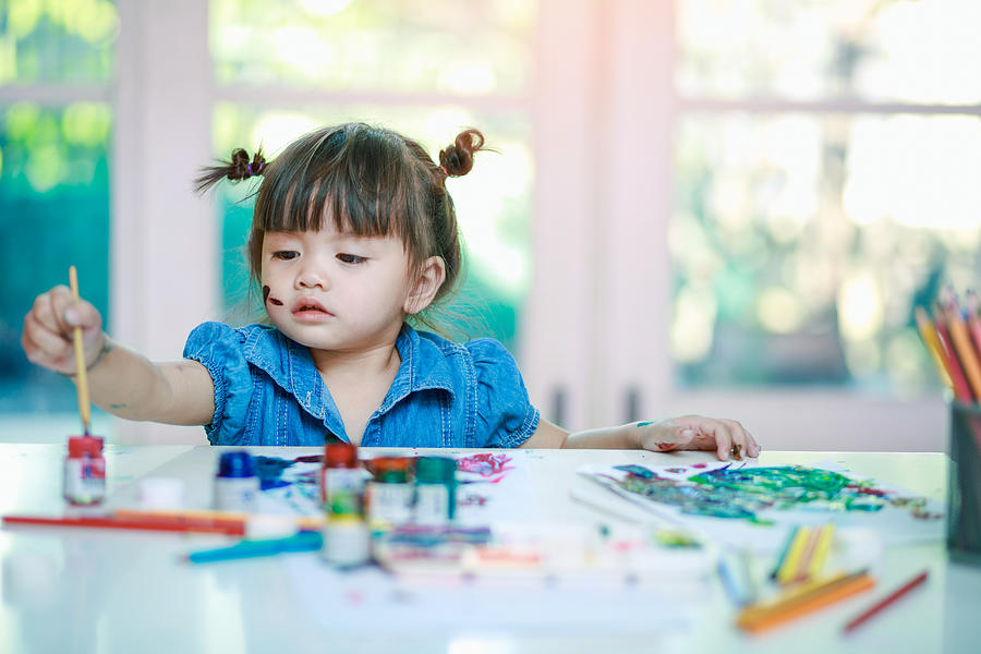 Little Girl Painting With Paintbrush And Colorful Paints On Desk Background Photograph by Busakorn Pongparnit