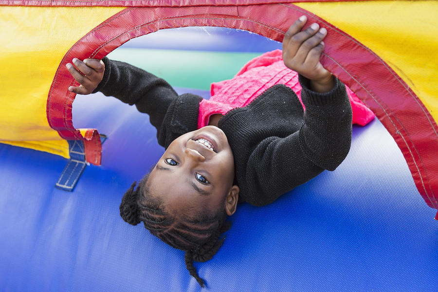Little girl playing in bounce house Photograph by Kali9