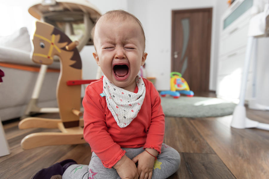 Little Girl Sitting On The Floor At Home And Crying. One Year Old Baby Crying Photograph