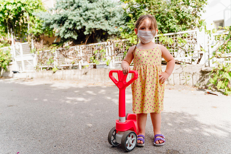 Little girl with a scooter and a medical mask Photograph by Phynart Studio