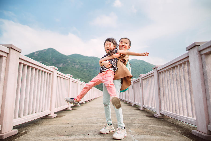 Little sibling playing joyfully on bridge in sunny day Photograph by Images By Tang Ming Tung