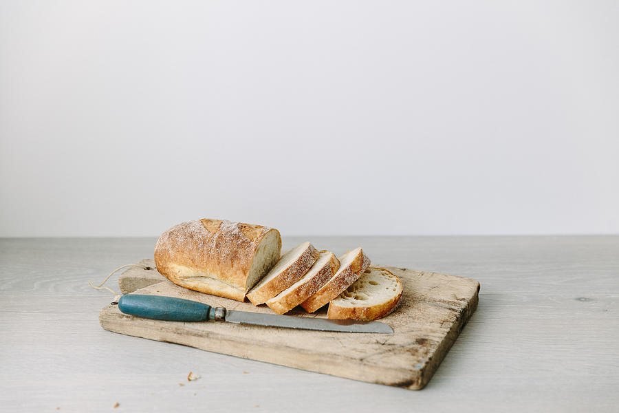 Loaf of sliced bread on a chopping board Photograph by Emmaduckworth