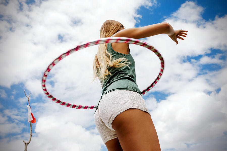 Long woman hula hooping on blue cloudy skies Photograph by Hello World