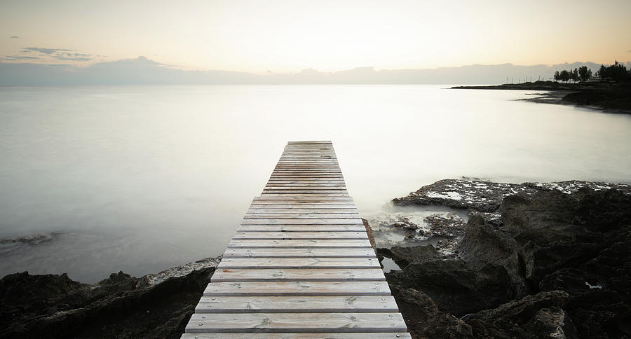 Long wooden pier in the sea at sunrise. Photograph by Michalakis Ppalis