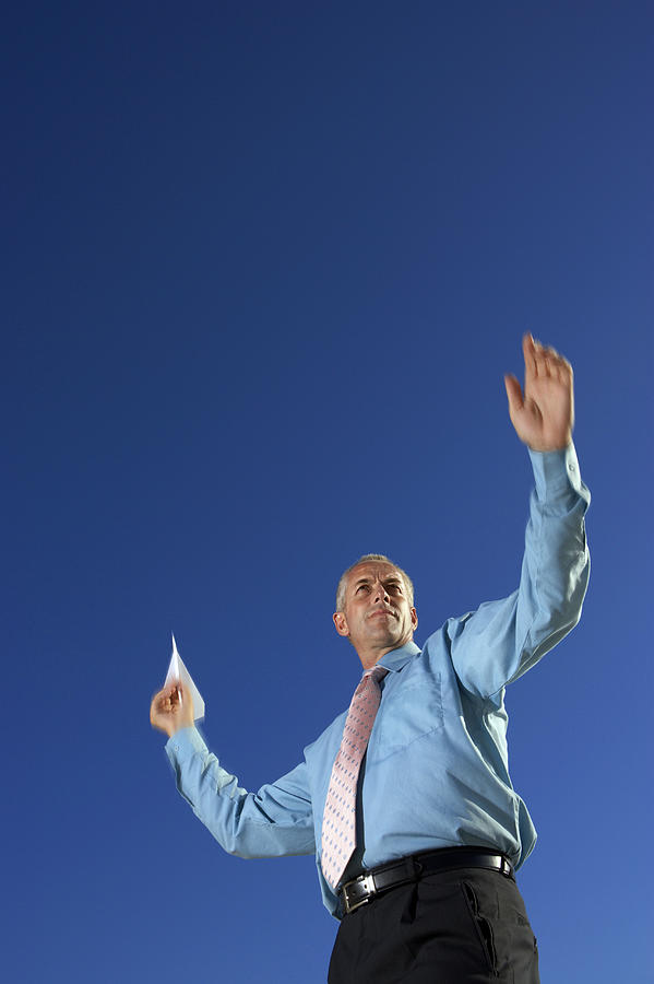 Low Angle of a Businessman Throwing a Paper Aeroplane Photograph by John Cumming