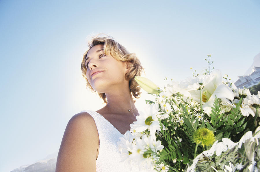 Low Angle Tilted Shot of a Serene Bride Holding a Bouquet of White Flowers Photograph by B2M Productions