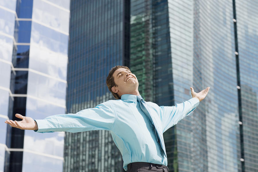 Low angle view of a businessman standing with his arms outstretched Photograph by Glowimages