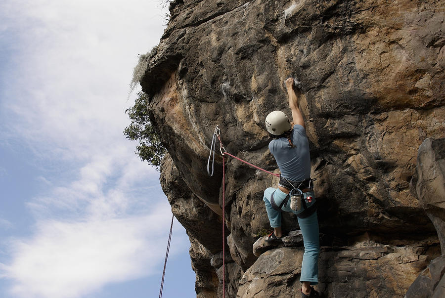 Low angle view of a female rock climber scaling a rock face Photograph by Glowimages