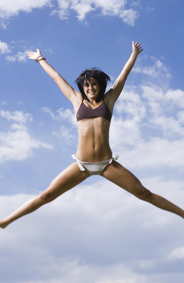 Low angle view of a young woman jumping Photograph by Rubberball