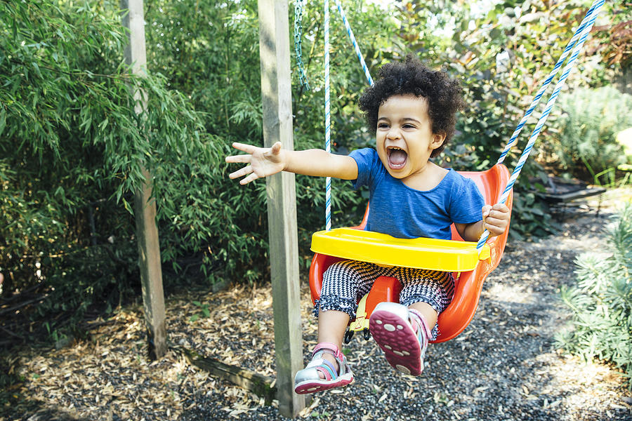 Low angle view of mixed race girl shouting on swing Photograph by Inti St Clair