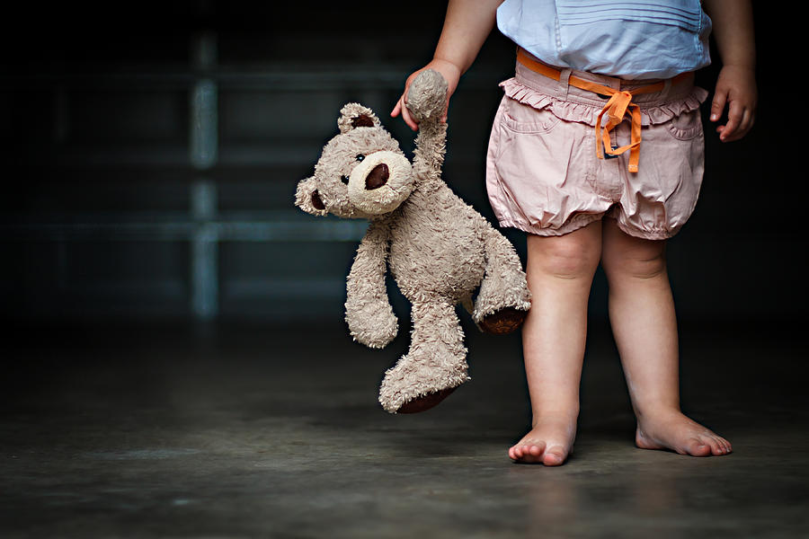 Low section of a girl holding her teddy bear Photograph by Laurenspolding