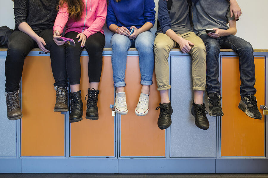 Low section of schoolchildren (12-13) sitting on lockers Photograph by Astrakan Images