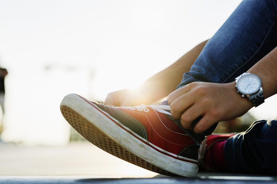 Low section of teenage girl tying shoe lace at skate park Photograph by Astrakan Images