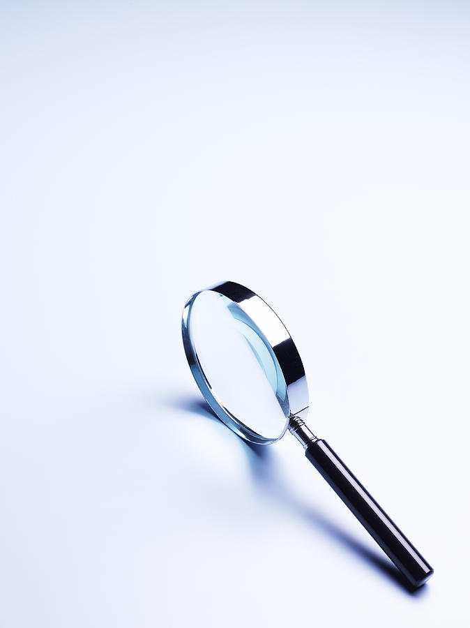 Magnifier on pale blue background with copy space Photograph by Peter Dazeley