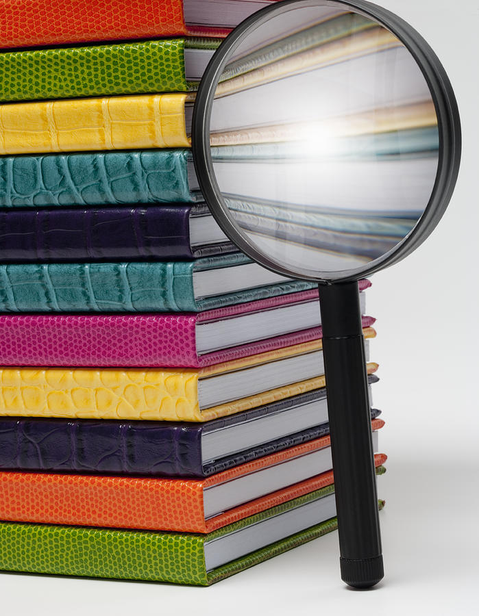 Magnifying glass next to colorful books Photograph by Gary S Chapman