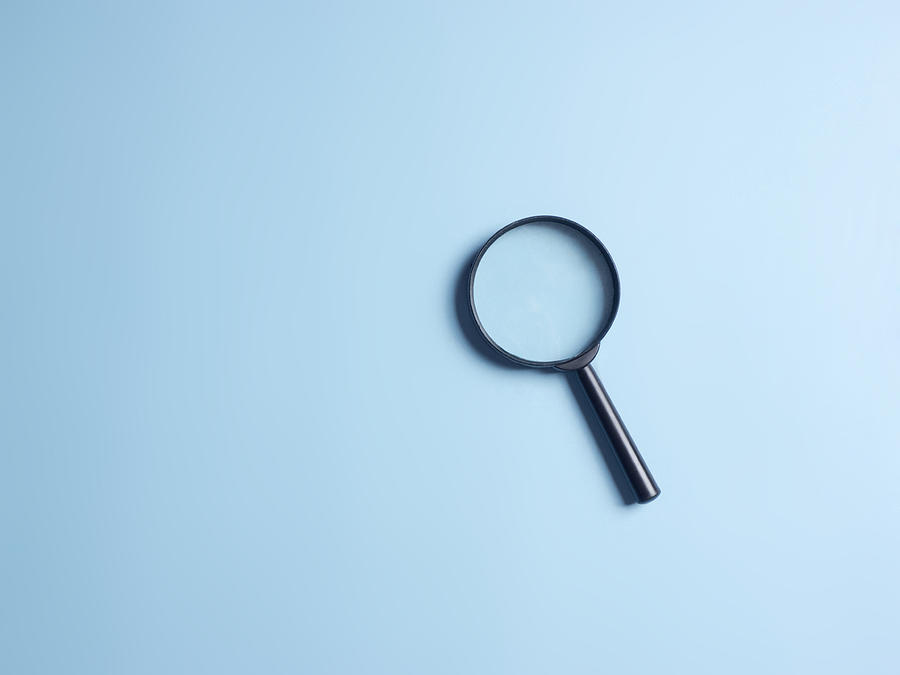 Magnifying glass on blue colour background with copy space. Searching information data concept Photograph by A. Martin UW Photography