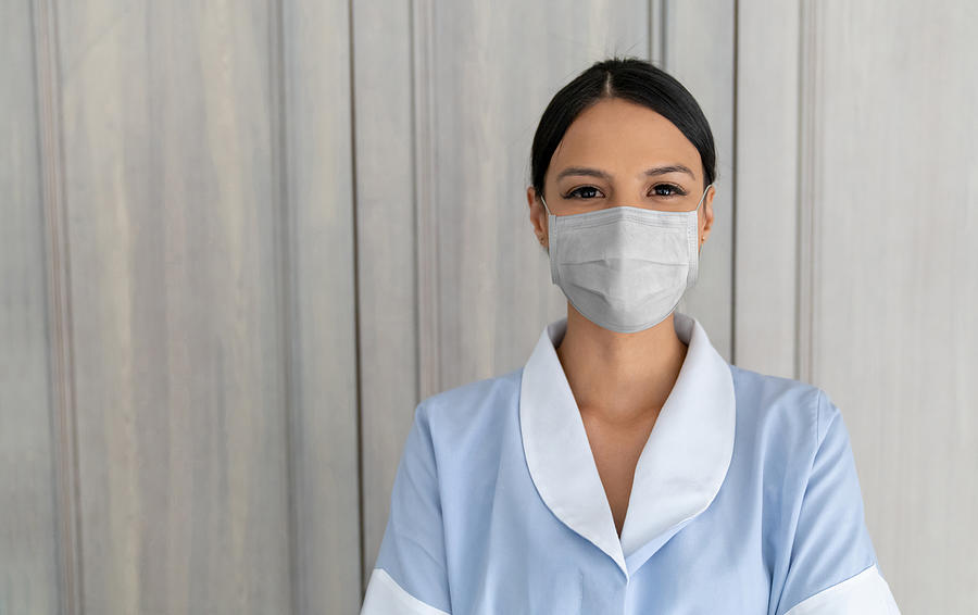 Maid wearing a facemask to avoid the spread of coronavirus while working at a hotel Photograph by Andresr