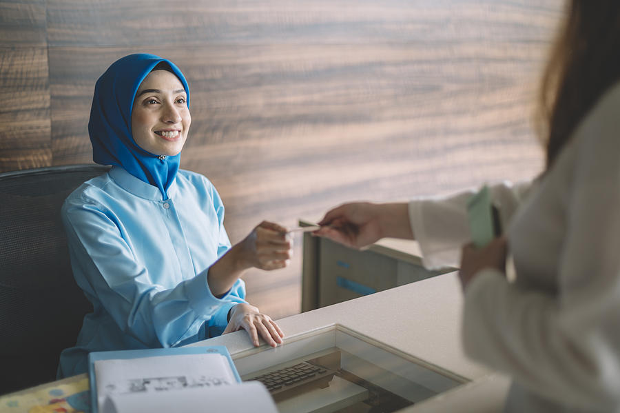malaysia hospital registration counter asian female receptionist getting payment from the female hijab Muslim patient accepting her credit card Photograph by Chee Gin Tan