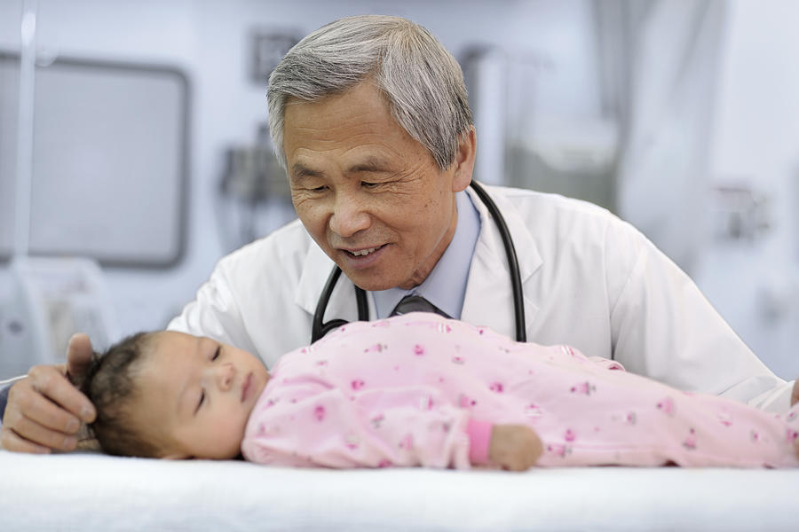 Male Asian doctor examining baby girl. Photograph by Francisblack