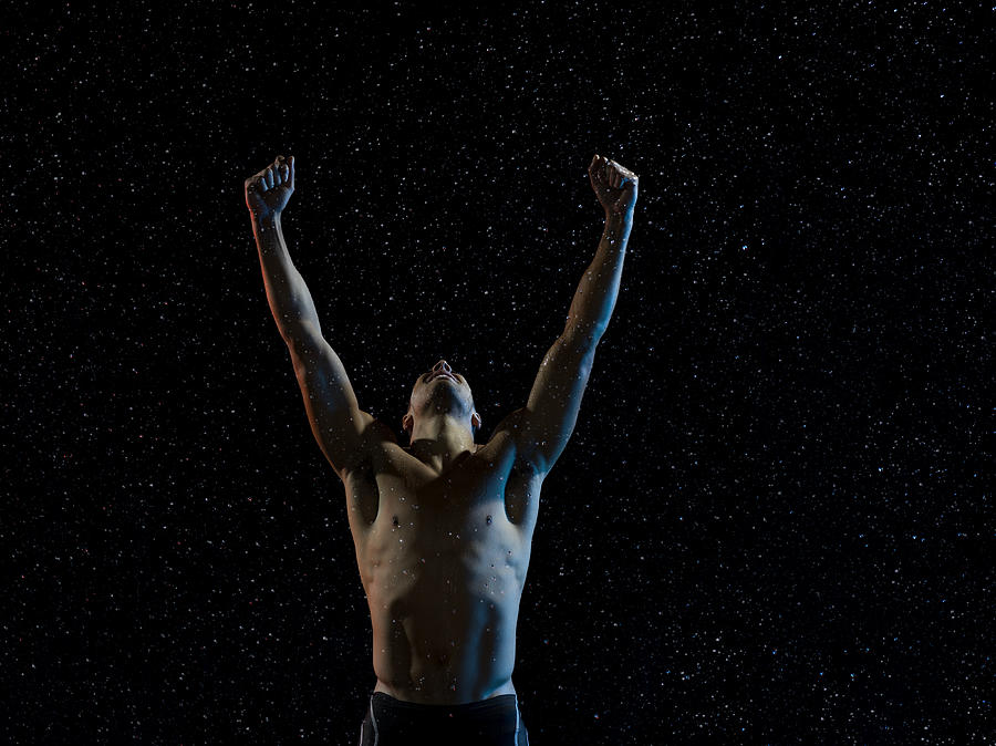 Male athlete raising arms in victory in rain Photograph by Jonathan Knowles