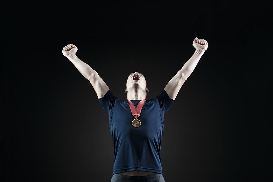Male athlete shouting with arms raised in victory Photograph by PhotoAlto/Milena Boniek