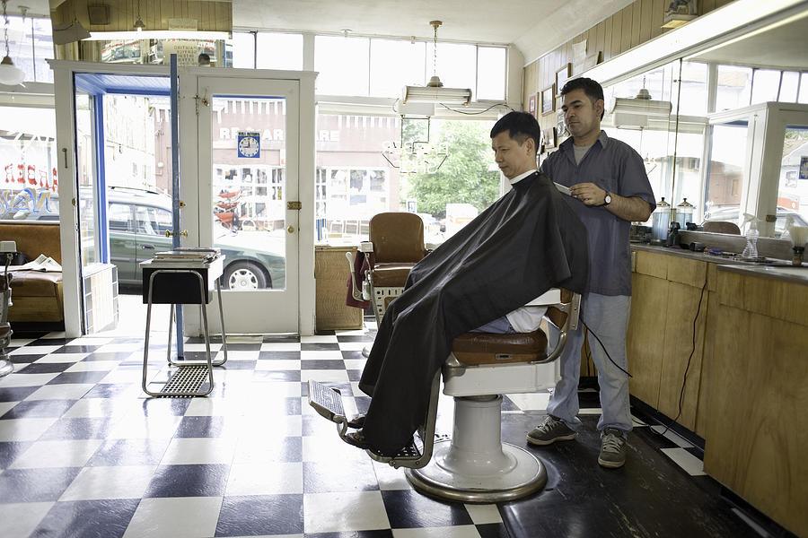 Male barber cutting mature mans hair in barber shop Photograph by Geoff Manasse