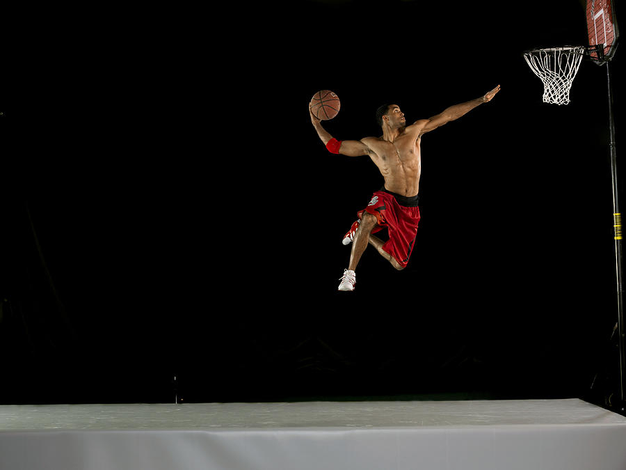 Male Basketball Player Jumping in Mid Air and Aiming for the Hoop, Studio Shot Photograph by 10000 Hours