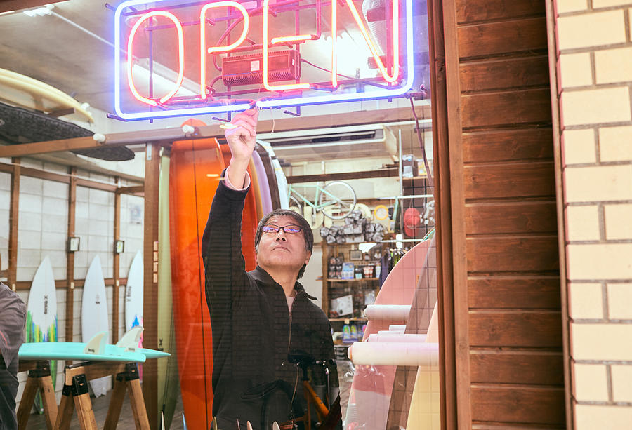 Male business owner turning on neon Open sign in shop window Photograph by Yoshiyoshi Hirokawa