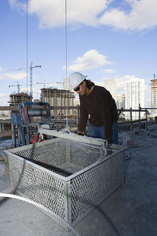 Male construction worker leaning against a basket at a construction site Photograph by Glowimages